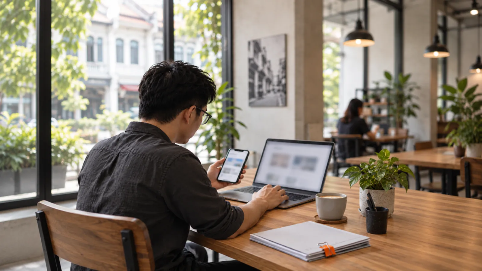 A business owner compares a blurred website on a phone and laptop.